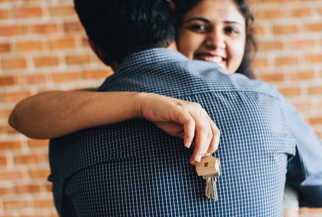 A couple hugging holding a house key during a post-wedding move